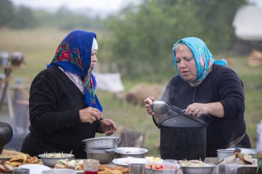 Belarus, Gomel bölgesi, 20 Temmuz 2022. Mülteci kampı. Mülteci kadınlar ve erkekler mülteci kampında dışarıda yemek hazırlıyorlar..
