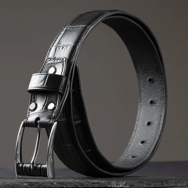 Black leather belt on a dark background. Men\'s belt.