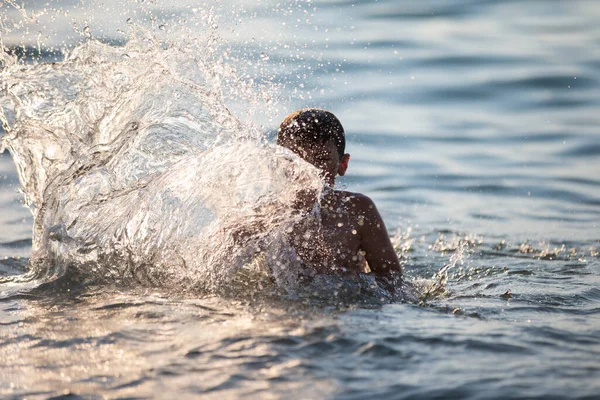 幸せなティーンエイジャーは海の波で遊んでいます 少年は海で泳いでいる — ストック写真