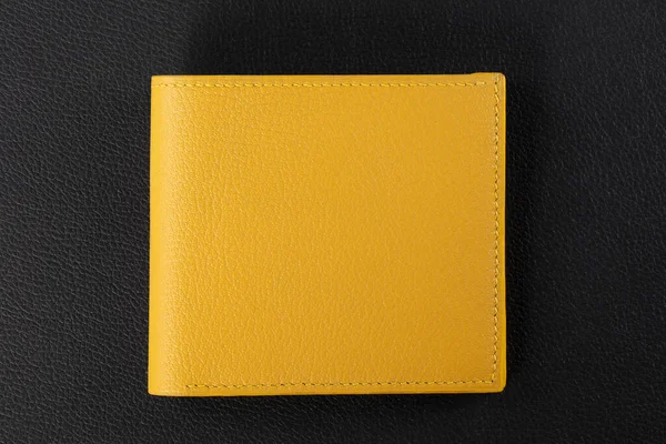Leather products. Wallet business card holder made of yellow leather on a black background.