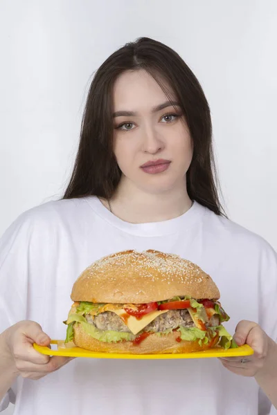 A woman is holding a big barbecue hamburger sandwich on the background. Fast food concept. The girl has a huge hamburger.