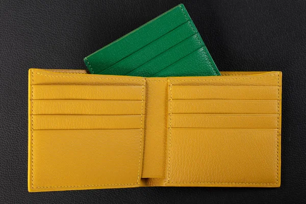 Leather products. Wallet business card holder made of green and yellow genuine leather on a black background.