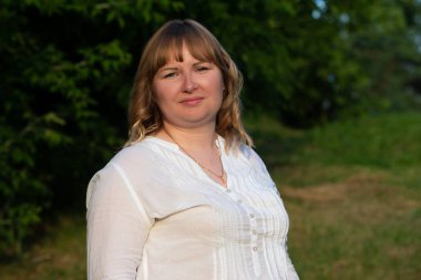 Mavi gözlü tombul bir sarışın kameraya bakar..