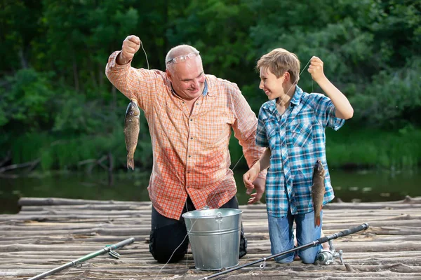 爷爷和孙子用钓竿和鱼钓鱼 夏天在村里钓鱼 — 图库照片