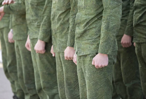 Line of male soldiers in military clothes.