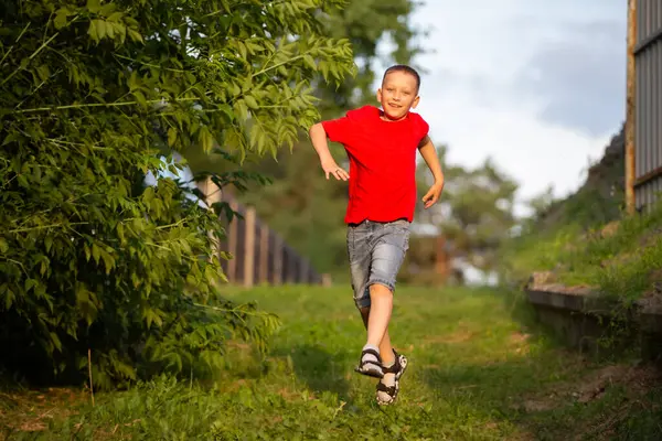 一个快乐的男孩沿着夏日的小路奔跑 — 图库照片
