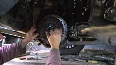 Otomobil teknisyeni araba basınç plakası ve yeni debriyaj diskini araba motoruna takıyor