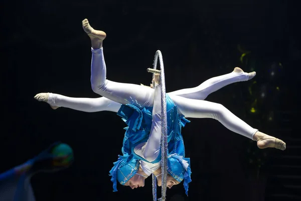 Two acrobat girls show a circus number on a dark background. Acrobatic performance.