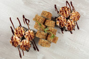 Beyaz ahşap arka planda çeşitli suşi ruloları var..