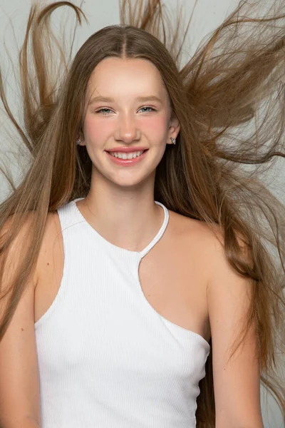 Happy blonde with long flowing hair. Portrait of a girl with a smile.