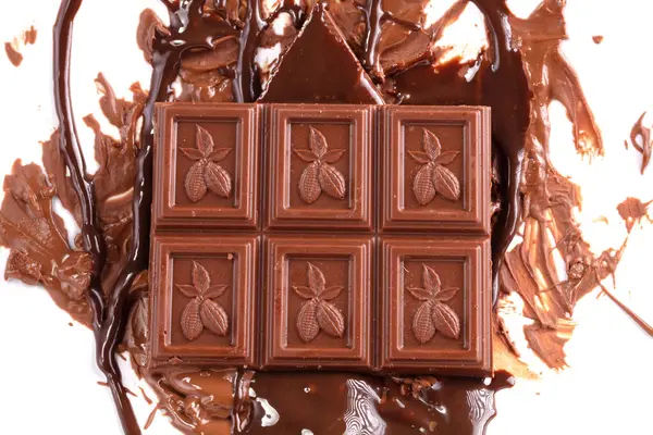 Sweet melted chocolate background with chocolate squares on which cocoa beans are drawn. Mass of chocolate.