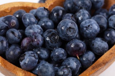 Beyaz arka planda ahşap bir tabakta yabanmersini..