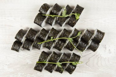 Beyaz ahşap arka planda çeşitli suşi ruloları var..