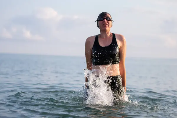 Woman swimmer jump out of sea water water with streaming splashes.