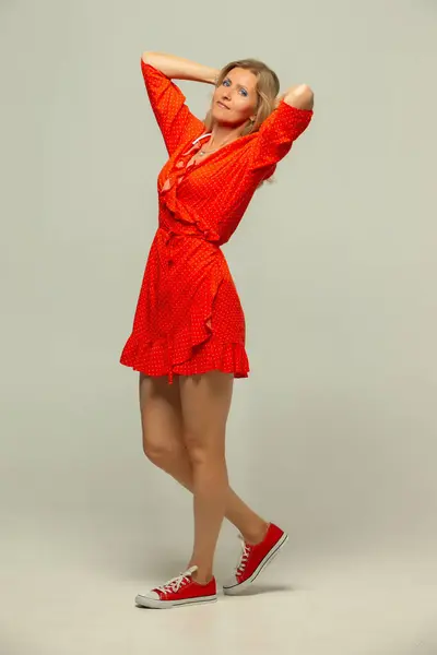 Full-length photo of a beautiful middle-aged woman in red clothes with a positive mood.