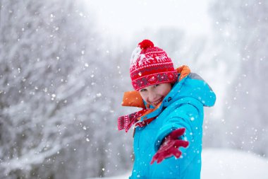 Karlı bir ormanda küçük mutlu çocuk elini uzatıyor. İyi kış tatilleri..