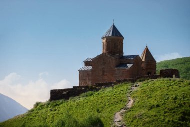 Stepantsminda yakınlarındaki Kazbegi dağlarındaki Kutsal Üçlü Kilisesi 'nin yakın görüntüsü arka planda Kafkas dağları görülüyor.