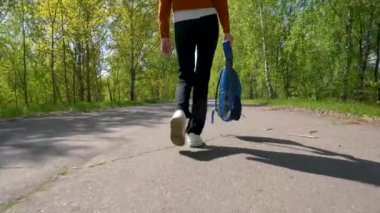 Sırt çantalı bir kızın bacakları asfalt yolda yürüyor..