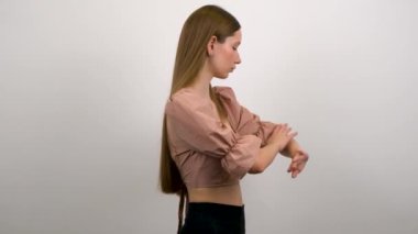 Genç, uzun saçlı sarışın kız gri arka planda kameraya poz veriyor..