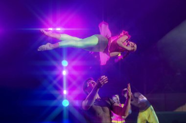 Uçan bir akrobat sirk ışıklarında karmaşık bir numara yapar..