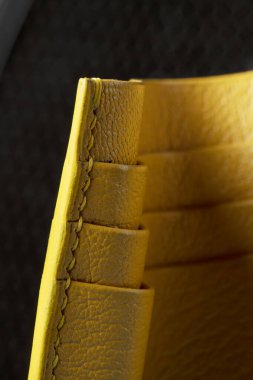 Siyah arka planda sarı deri bir cüzdan sahibi var..