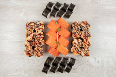 Beyaz ahşap arka planda çeşitli suşi ruloları var..