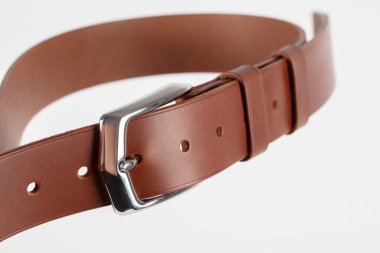 Açık kahverengi klasik deri kemerin bir parçası. Gri bir arka planı var..