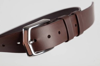 Gri bir arka planda tokası olan kahverengi bir klasik kemerin parçası..