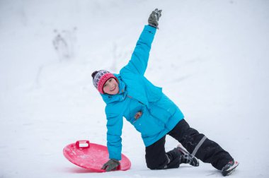 Bir çocuk kış tatilinde kızağa biner..