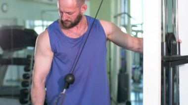 Spor salonunda bir adam çalışıyor. Pazılarını şişiriyor..