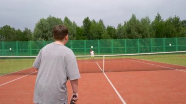 Tenis kortunda, iki çocuk antrenman sırasında tenis oynuyorlar..
