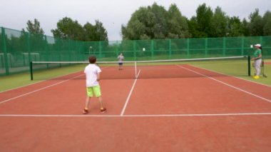 Tenis kortunda, iki çocuk antrenman sırasında tenis oynuyorlar..