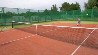 Tenis kortunda, iki çocuk antrenman sırasında tenis oynuyorlar..