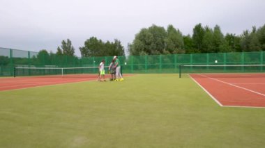 Tenis kortunda, genç çocuklar antrenmanlarına tenis antrenmanlarıyla başlarlar. Tenis topu dolu bir araba getirdiler..
