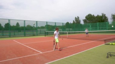Tenis kortunda, iki çocuk antrenman sırasında tenis oynuyorlar..