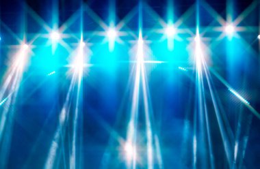 Sahne ışıklarının beyaz dumanındaki beyaz ışık huzmeleri ile soyut mavi arkaplan.