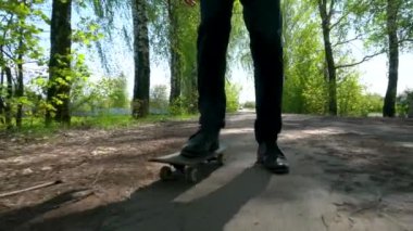 Siyah pantolonlu ve siyah çizmeli bir adamın bir huş ağacında kaykay yapmayı öğrendiği yakın plan..