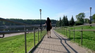 Elbiseli bir kadın parkın oradaki merdivenlerden aşağı iniyor. Arkadan görüntüle.