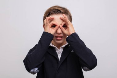 Genç bir çocuk parmaklarıyla dürbün ya da gözlük gösteriyordu..