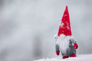 Kırmızı şapkalı Noel oyuncağı cücesi kışın arka planda