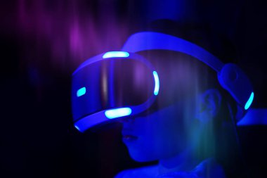 Mavi sanal gerçeklik kulaklığı takan biri. O kişi kameraya bakıyor. Sanal dünyaya girmeye hazırlanan kişinin heyecan ve beklenti anlayışı