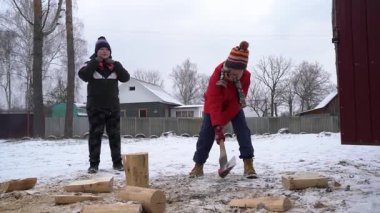 İki çocuk karda şakalaşarak odun kırıyor..