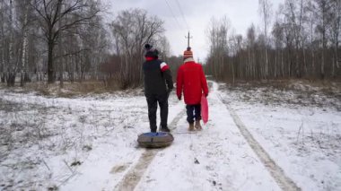 İki insan ormanda karlı yollarda yürür..