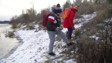 Çocuklar kışın karla birlikte nehir kenarını keşfediyorlar.