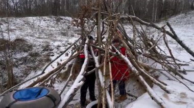 Çocuklar dallarla bir kış sığınağı inşa ediyorlar..
