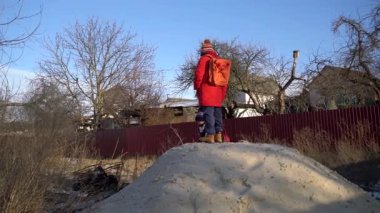 Çocuk güneşli bir kum tepeciğinde oynar.