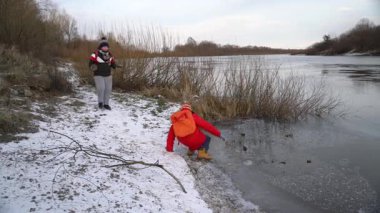 Buzlu nehir kıyısını keşfederken çocuk kayıyor.