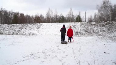 Çocuklar kayak yapmak için tepeye doğru yürüyorlar..