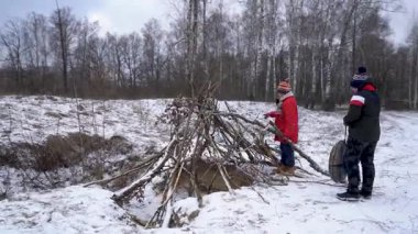 Çocuklar karlı ormanda bir barınak inşa ederler..