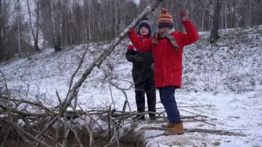 İki çocuk kışın bir sopa kalesi inşa eder..